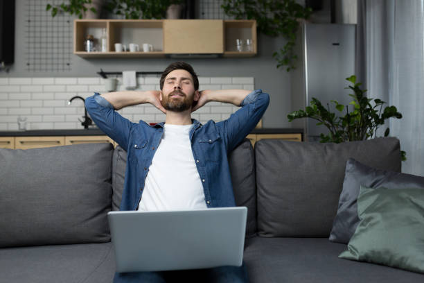 istock The man at home is resting while working on a laptop, sitting on the couch, threw his hands behind his head dozing off 1386725695