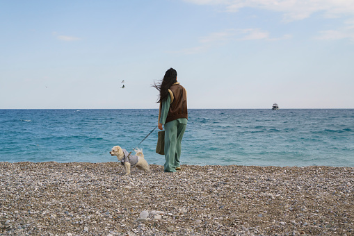 Young woman walking on the beach with her terrier puppy