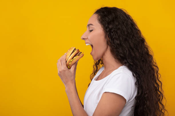 istock Funny Lady Holding Burger Biting Sandwich At Studio 1386727274