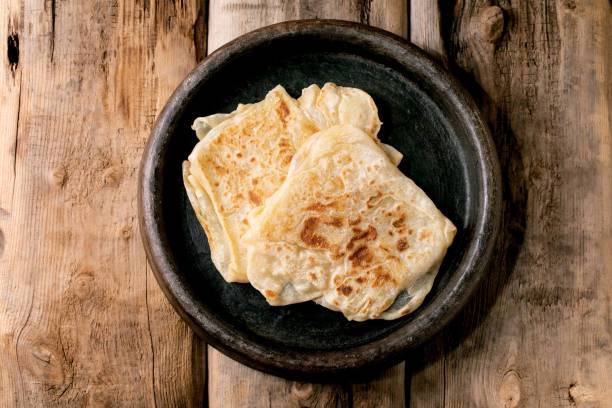 Traditional indian homemade roti flatbread in ceramic dish Stack of traditional indian homemade roti flatbread in old ceramic dish over old wooden background. Top view, copy space roti canai stock pictures, royalty-free photos & images