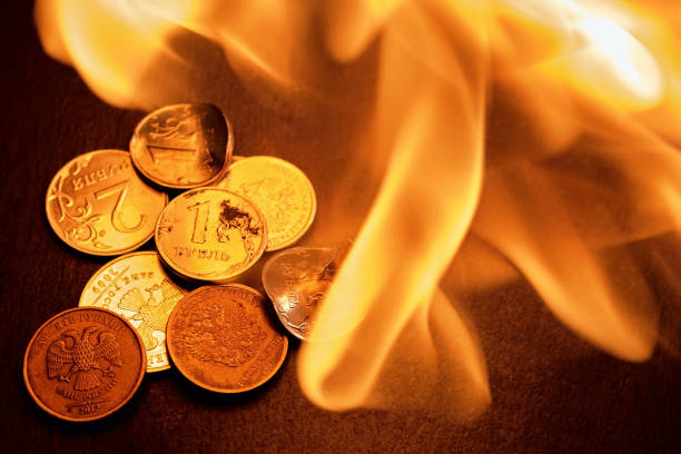 Russian coins, deformed and broken money on fire. The idea of the collapse of the ruble and the economy, sanctions against Russian aggression, layout on a black stone background stock photo
