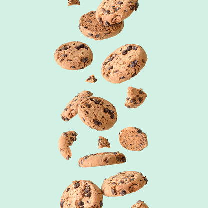 Chocolate chip cookie floating on a green background. Aesthetic sweet food concept.
