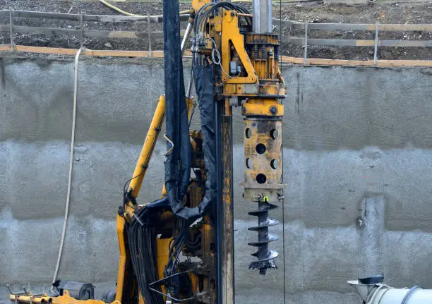 Photo of the drilling rig with a pipe drill drills holes for concreting the foundation columns and grouting the subsoil. wire reinforcing mesh cylinder shape, ready for installation on site, wrapped, trunk