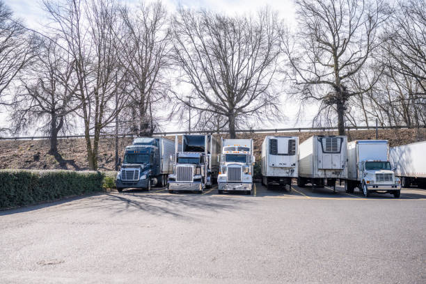 istock Different powerful big rigs semi trucks and semi trailers standing on the industrial parking lot taking a break and waiting for the next load for delivery 1386740645
