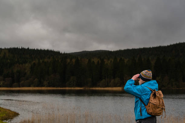 istock Retired man looking at a loch through binoculars 1386743624