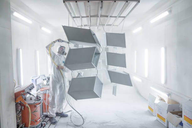 KYIV, UKRAINE - August 16, 2021: Powder coating of metal products in spray booth. Industry painting metal parts in paint booth. Coveralls worker with spray gun painting steel parts in painting chamber trabajador de overoles con pistola pulverizadora pintando piezas de acero en cámara de pintura o garaje de pintura. recubrimiento en polvo de productos metálicos en cabina de pulverización. recubrimiento de superficies de la industria de pintura de piez