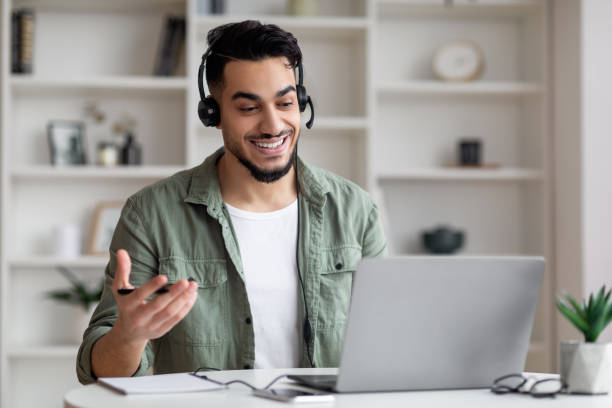 Teleconference Concept. Handsome Arab Guy In Headset Making Video Call With Laptop