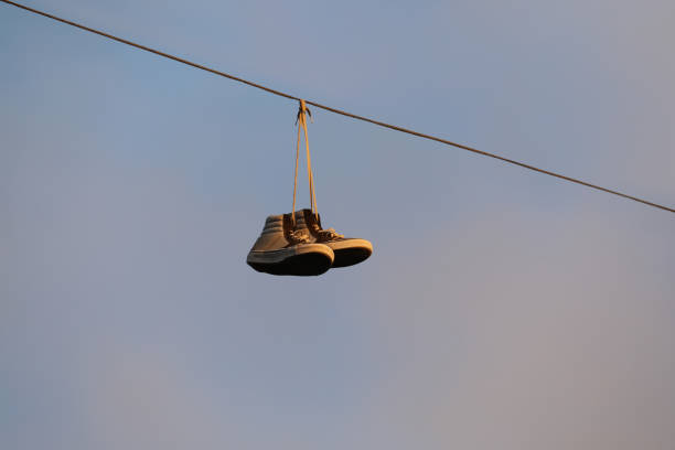 Old sneakers hanging on a powerline at sunset stock photo
