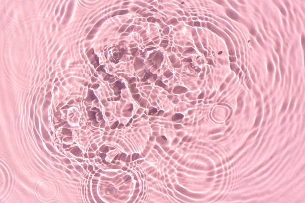 istock Drops on pink water background under sunlight. Top view, flat lay 1386753477