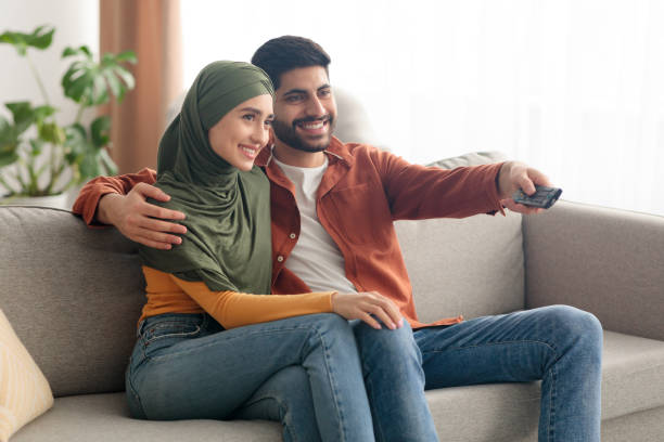 istock Side View Of Happy Middle Eastern Spouses Watching TV Indoors 1386757385