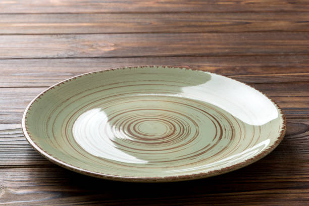 istock Perspective view of empty green plate on wooden background. Empty space for your design 1386759970