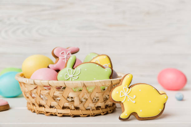 colorful easter cookies in basket with multi colors easter eggs on colored background . pastel color easter eggs. holiday concept with copy space - paastaart stockfoto's en -beelden