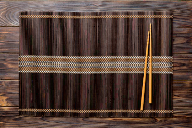 istock Two chopsticks and bamboo mat on wooden background. Top view, copy space 1386760044