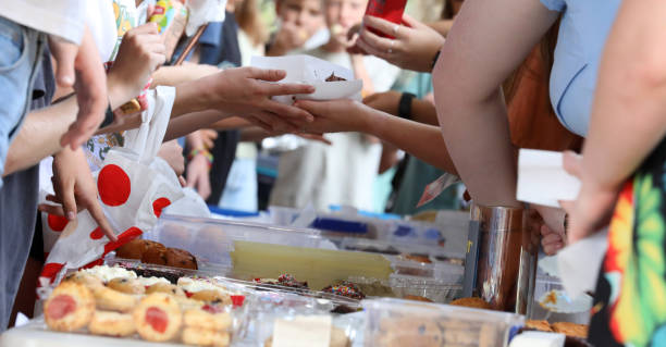 Cake and bake sale at a local community market or fundraiser event A close up of hands and food exchanging at a communty fair, fete or market stall. A typical bake or cake sale. fete stock pictures, royalty-free photos & images