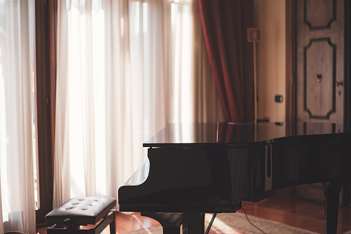 Art scene of a grand piano and beautiful sunlight radiating through the curtains of a room in nice moody style.