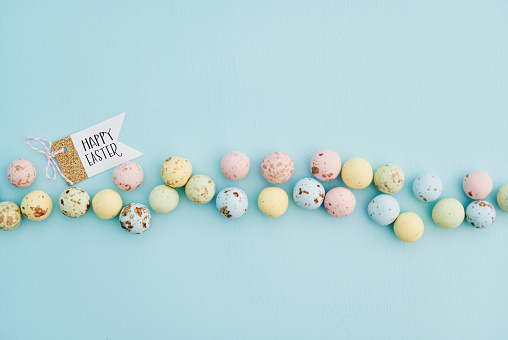HAPPY EASTER message with speckled Easter candy on a blue background
