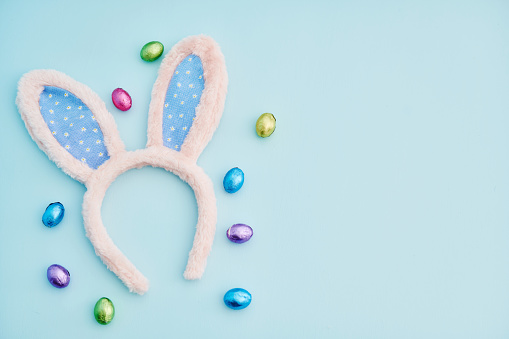 Blue Easter background with fluffy rabbit ears and Easter candy