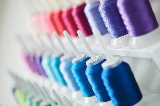 Collection of colorful spools of embroidery thread on a thread organizer hanging on a craft room wall