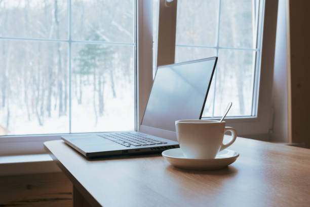 istock Cup and laptop on the table in front of the window. 1386791246