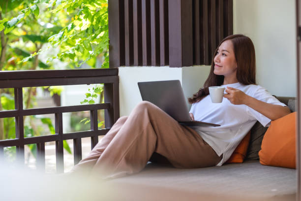istock Portrait image of a young woman using laptop computer for working or studying online while drinking coffee and laying on sofa at home 1386800781