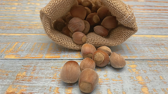 shelled hazelnuts in small wicker sack on wooden background