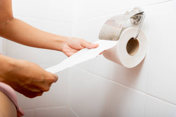 istock Closeup hand pulling toilet paper roll in holder for wipeCloseup hand pulling toilet paper roll in holder for wipe, woman sitting on toilet she taking and tearing white tissue on wall to towel clean in bathroom, Healthcare concept 1386806153