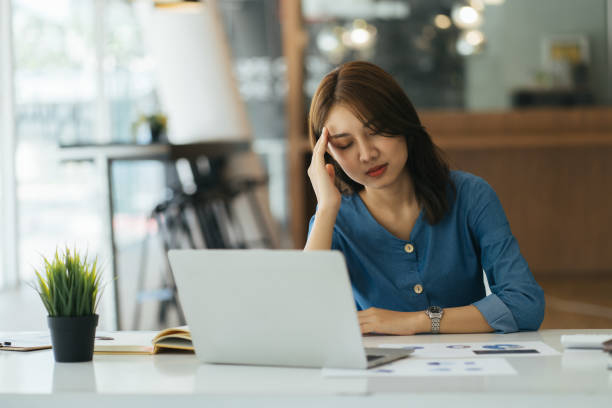 istock Stressed young woman doing paperwork at modern workplace. Stress concept 1386809439