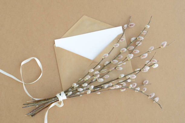 istock white greeting card, easter willow branches and kraft paper envelope  on a eco friendly cardboard background. Letter and spring bouquet, flat lay, top view 1386810299