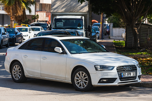 Antalya; Turkey – March 04 2022:   white  Audi A4  is parked  on the street on a warm  day against the backdrop of  park