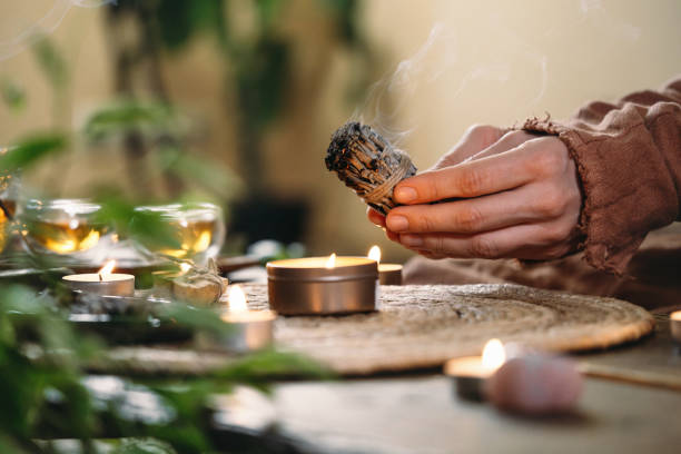 istock Woman hands burning white sage, before ritual on cadle 1386814608