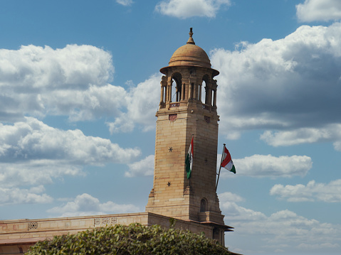 Parliament building tower with the flags of India in New Delhi, India.