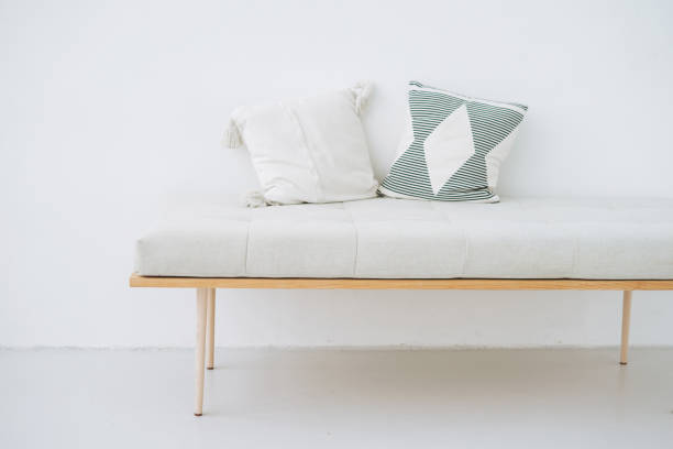 Minimalistic wooden bench with linen pillows in eco-style on white wall background