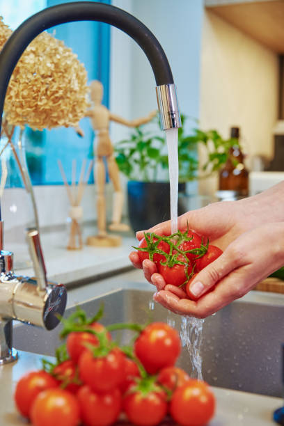 istock Woman washing tomato at kitchen sink 1386816558