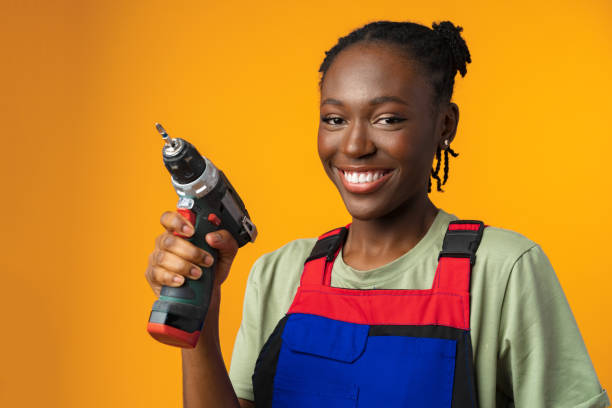 чернокожая афроамериканская модель в униформе держит инструмент для ремонта отвертки на желтом фоне - holding screwdriver стоковые фото и изображения