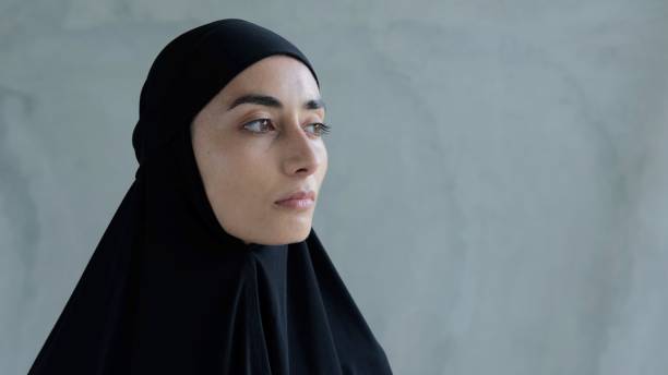 黒いヒジャーブを着た女性は、シャリーア法違反に対する罰、イスラム教徒の家族の中での自由が制限されているイスラム女性の厳しい生活を恐れて、心配して横を向いています - freedoms ストックフォトと画像