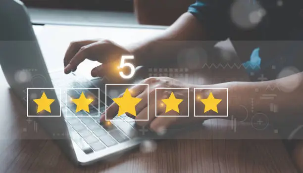 Photo of Close up man using Lap top for rating feedback from customer service with annual survey with five gold star icon. Business annual satisfaction survey concept. User reviews and feedback online.