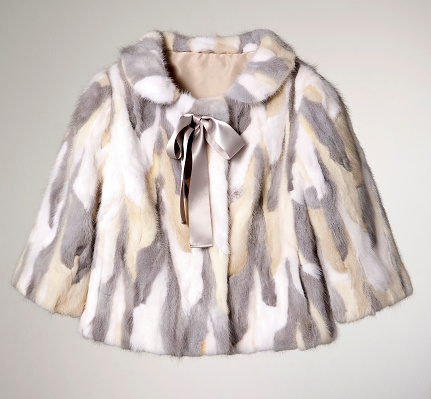 Fashionable fur coat on gray background