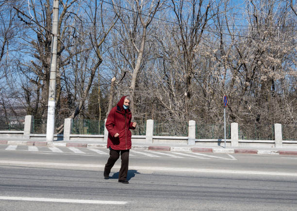 una anciana cruza la calle a toda prisa. - título del álbum fotografías e imágenes de stock