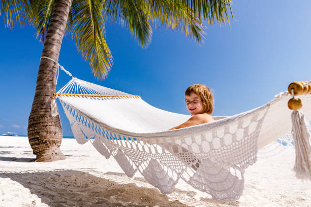 istock Happy boy enjoying in hammock on the beach. 1386823668