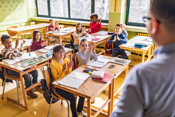 istock Large group of happy students applauding to their elementary teacher at school. 1386825244