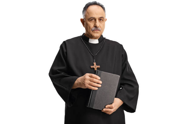 istock Serious priest holding a bible and looking at camera 1386827618