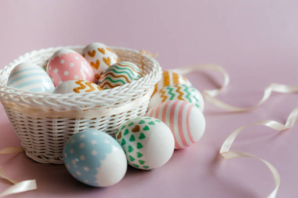 istock Easter eggs in pastel colors with a pattern in white basket on pink background. 1386828466