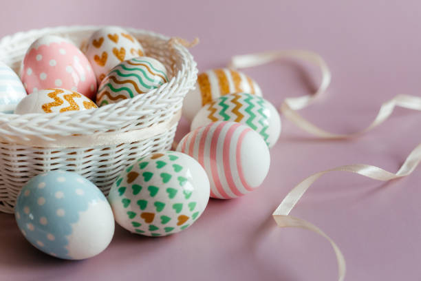 istock Easter eggs in pastel colors with a pattern in white basket on pink background. 1386828478