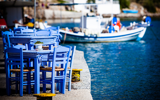Seaside blue table and chairs open cafe outdoor restaurant in Greece on sea shore. Summer vacation on resort.