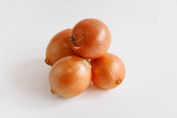 Small heap of onions with yellow peel on white background, organic food, studio shot