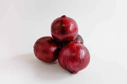 Small heap of Spanish onions with red peel on white background, organic food, studio shot