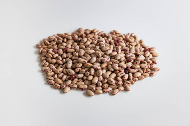 Small heap of brown textured beans on white background, organic food, studio shot