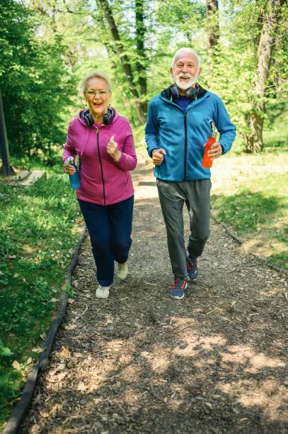 istock Smiling senior couple jogging in the park 1386829921
