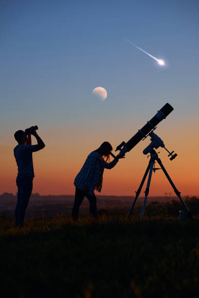 istock Couple stargazing together with a astronomical telescope, looking at planets, stars, lunar eclipse and meteor shower. 1386830261