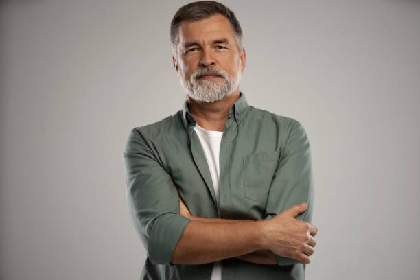 portrait of smiling mature man standing on white background - 50 54 jaar fotos stockfoto's en -beelden